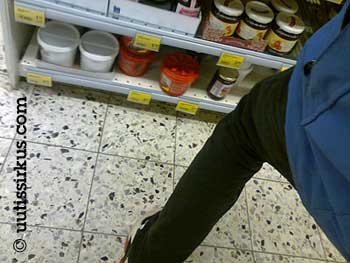 Asiakas on kyykistymäisillään hillopurkkihyllyn ääreen