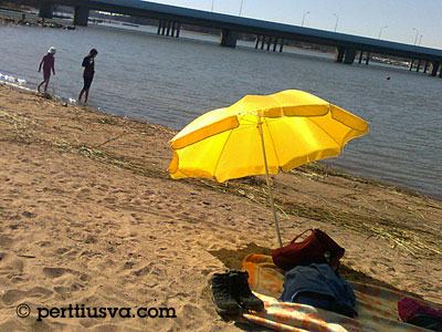 hiekkaranta meren äärellä ja keltainen aurinkovarjo