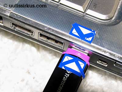 sininen tarra muistitikun päällä ja tietokoneessa usb-liittymän yläpuolella