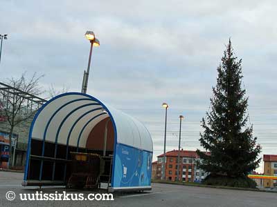 Joulukuusen vierestä saa ostoskärryt Jumbon pihamaalla