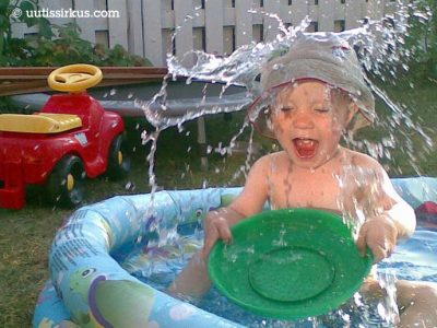 taapero roiskuttaa vettä päälleen puhallettavassa kahluualtaassa