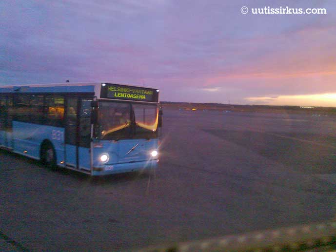 sininen lentokenttäbussi ajaa aamun sarastuksessa kentällä