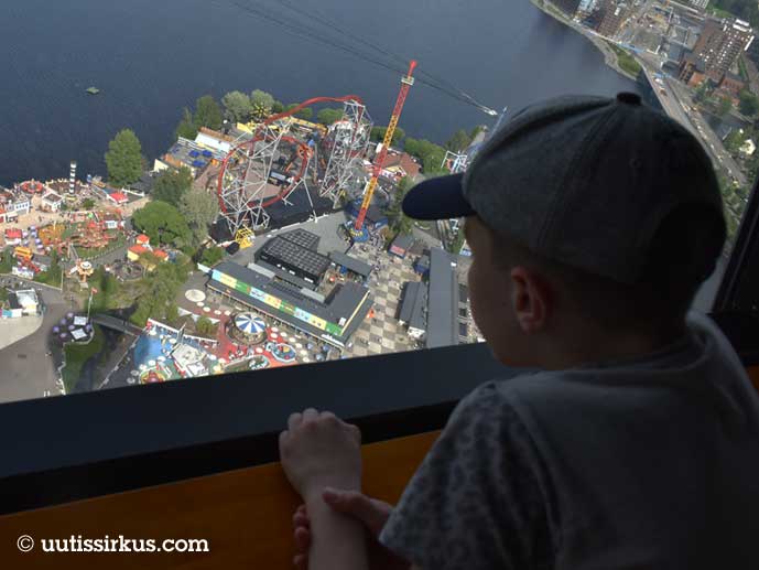 poika katsoo lippalakki päässään Särkänniemen huvipuistoa Näsinneulan ikkunasta