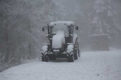 lumen kuorruttama traktori ajaa lumihangessa
