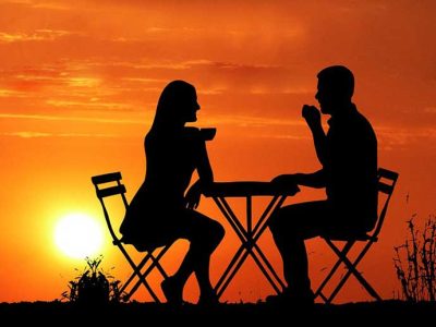 Mies ja nainen ravintolapöydässä, siluetit, takana auringonlasku