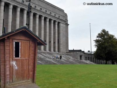 eduskuntatalon edessä nurmella ulkohuussi
