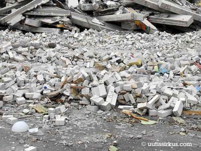 rakennuksen raunio, edessä vaaleiden tiiliskivien kasoja, taaempana katkenneita betonipalkkeja