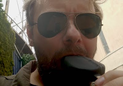 mies aurinkolasiessa syö jäätelöpuikkoa