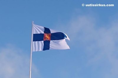 Suomen valtiolippu liehuu sinistä taivasta vasten