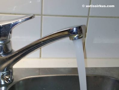 lähikuvassa vesihana, josta valuu vettä keittiön tiskialtaaseen