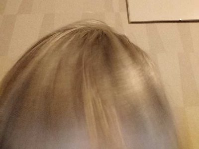 naisen vaaleat hiukset, lienee kumartuneena lattialle katsoakseen kuvaa, joka niinikään lattialla