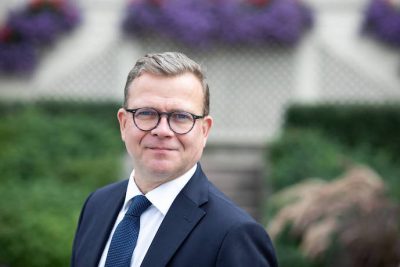 Pääministeri Petteri Orpo, rintakuva kesäisen vihreässä maisemassa vuonna 2023